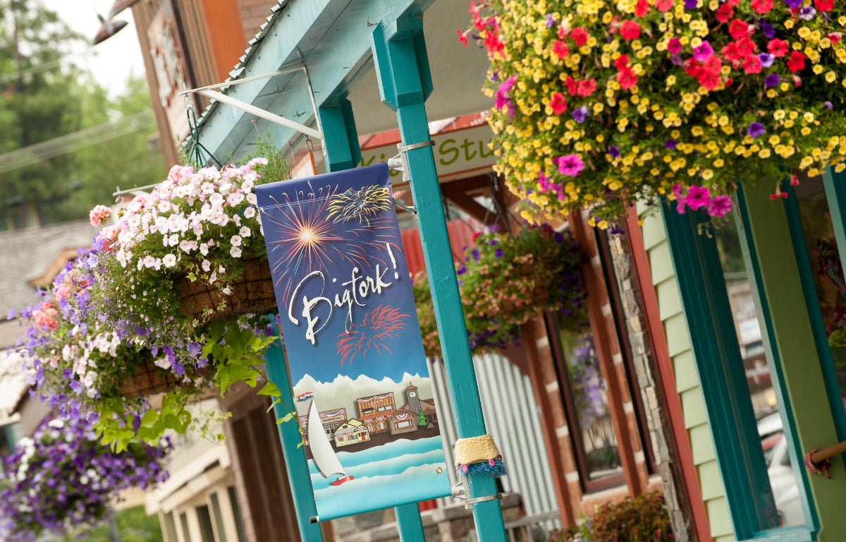 A Bigfork banner in front of a store with hanging flower baskets